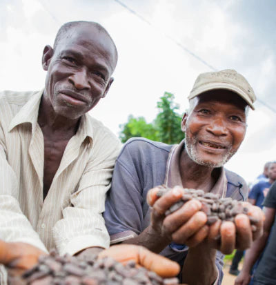 Two smiling cocoa farmers with hand fulls of cocoa beans